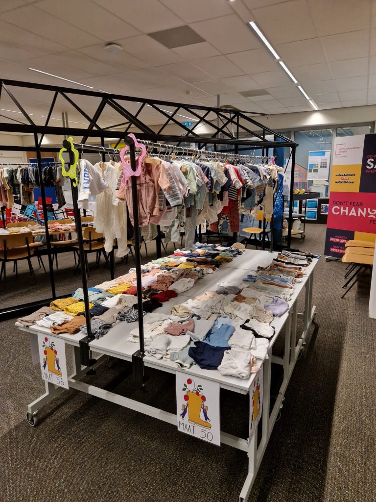 Small baby clothes arranged on a table and rack.